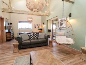 A living room with a sofa, hanging chair, and wooden flooring. - Rathmell, Long Preston (Skipton)