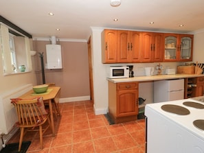 A kitchen with wooden cabinets, a microwave, a stove, and a dining area with chairs.