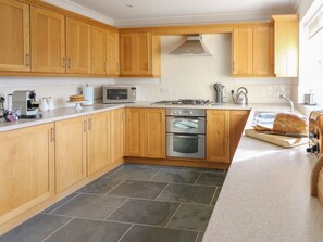 Una cocina con armarios de madera, un microondas, un horno y una hogaza de pan sobre la encimera.