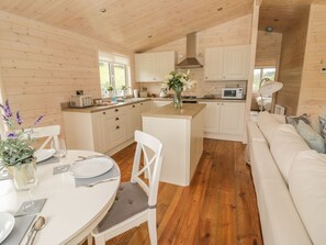Interior de una cabaña de madera con comedor, cocina y sala de estar.