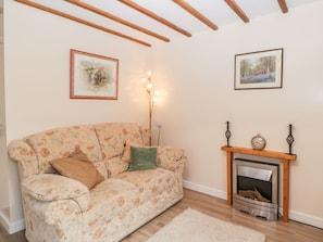 A living room with a floral sofa, a fireplace, and two framed pictures on the walls.