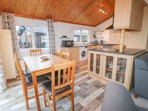 Una cocina acogedora con armarios de madera, una mesa de comedor y una lavadora.