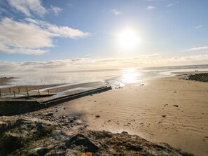 Une plage avec un ciel dégagé, un rivage sablonneux et une mer calme.