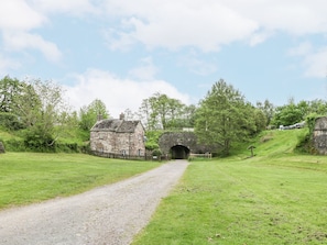 A rural road leading to a stone bridge and a stone building.