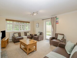 A living room with a sofa set, a coffee table, a TV, and a window with curtains.