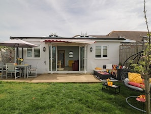 Una casa con patio, mobiliario exterior y un porche cubierto.
