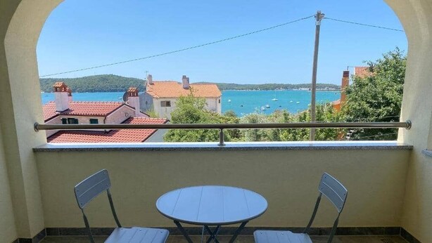 Ein Balkon mit Meerblick, zwei Stühle und ein kleiner Tisch.