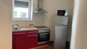 Eine kompakte Küche mit Einbauofen, Mikrowelle und Edelstahl-Kühlschrank.