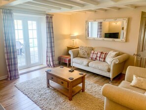 Un salon avec un canapé, une table basse, une lampe et un miroir au mur.