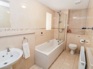 Un baño con bañera, lavamanos, inodoro y ducha con mampara de vidrio.