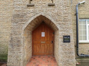 A stone building with a wooden door and a sign reading 'Castle Top Hotel.'
