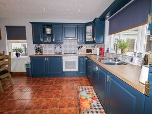 A kitchen with blue cabinets, a wooden countertop, a gas stove, a microwave, and a sink.