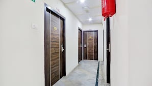 Un couloir avec des portes en bois, un extincteur et un panneau indiquant la sortie.