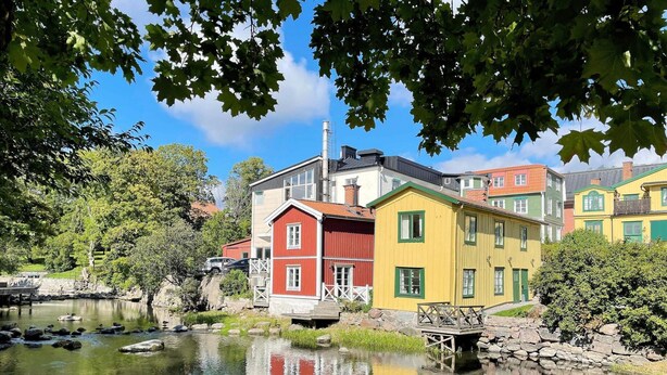 Une rangée de maisons colorées bordant une rivière paisible, avec un quai en bois.