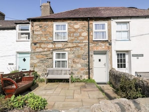 A stone building with multiple windows and a bench in front.