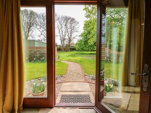 Une porte donnant sur un jardin avec un chemin de gravier et des plantes en pot.