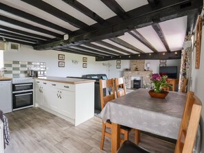 A kitchen with white cabinets, a wooden dining table, and a stone fireplace.
