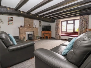 A living room with a fireplace, leather sofas, a television, and a stone wall.