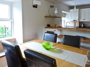 A dining area with a wooden table, black chairs, a green bowl, and a white table runner.