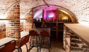 A bar area with brick walls, a counter, and stools.