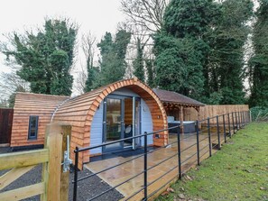 A wooden cabin with a curved roof, a glass door entrance, and a wooden deck.