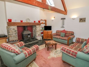 A cozy living room with a fireplace, two sofas, a coffee table, and a television. - Beudy Bach, Y Felinheli (Caernarfon)