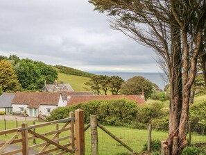 Un paysage rural avec des maisons, une porte en bois et une vue sur la mer.