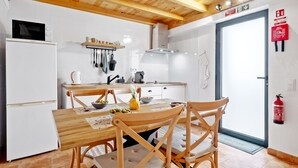 A kitchen with white cabinets, a microwave, a stove, and a dining table with chairs. - N T House by Homie in Porto Moniz (Porto Moniz)