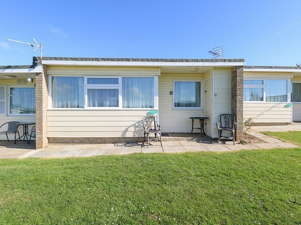 A two-story mobile home with a patio area, a small table, and two chairs.