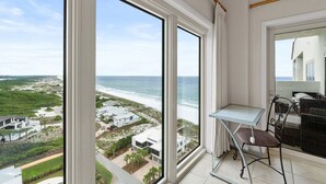 Een balkon met uitzicht op het strand en de oceaan, een klein tafeltje en een stoel.
