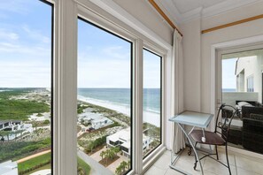 Ein Balkon mit Blick auf Strand und Meer, ein kleiner Tisch und ein Stuhl.