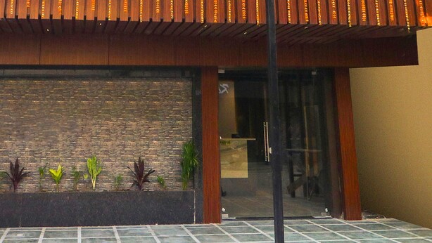 A building entrance with a tiled floor, a brick wall, and a wooden overhang. - Townhouse Birsa Railway Stadium Ranchi (Ranchi)