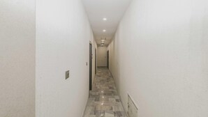 A narrow hallway with white walls and a patterned floor, leading to a door at the end. - Townhouse Birsa Railway Stadium Ranchi (Ranchi)