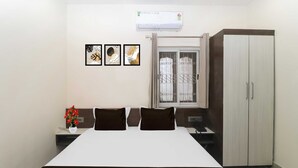 A bedroom with a bed, a wardrobe, a window with curtains, and three framed pictures on the wall. - Townhouse Birsa Railway Stadium Ranchi (Ranchi)