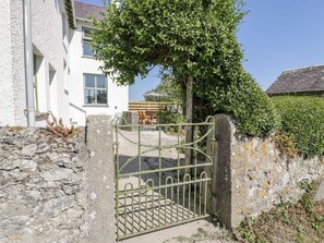 A white building with a stone wall and a metal gate.