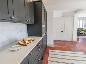 Een keuken met donkere kastjes, een wit aanrechtblad en een betegelde spatwand.