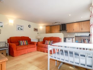 Una sala de estar con sofá, una mesa de comedor y una zona de cocina con armarios de madera y estufa.