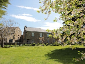 A stone building with a grassy courtyard and flowering trees. - St. Lawrence Rest, Warkworth (Morpeth)