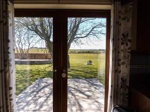 Una habitación con una puerta corrediza de vidrio que da a un patio con césped y árboles.