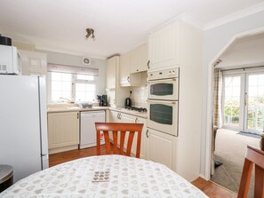 A compact kitchen with white cabinets, a stove, and a refrigerator.