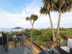 Eine Terrasse im Freien mit Tisch, Stühlen und einer Weinflasche.