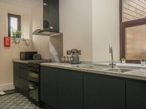 Una cocina equipada con estufa, horno, microondas, hervidor y pileta.