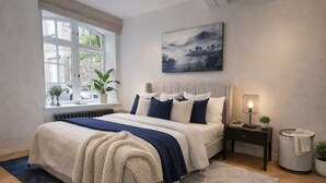A bedroom with a bed, a nightstand, a lamp, a window with plants, and a painting on the wall. - Luxury Covent Garden Residence – 2 Bed 2 Bath (London)