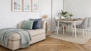 A modern living room with a sofa, a dining table with chairs, and framed pictures on the wall. - Luxury Covent Garden Residence – 2 Bed 2 Bath (London)