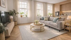 A modern living room with a sofa, coffee table, and potted plants. - Luxury Covent Garden Residence – 2 Bed 2 Bath (London)