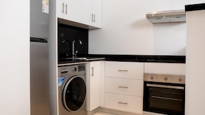 A compact kitchen with a washing machine, a stove, and a sink.