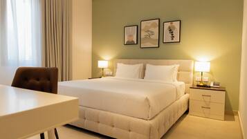 Ein Hotelzimmer mit Bett, Nachttischen, Schreibtisch und Stuhl. An der Wand hängen drei gerahmte Kunstwerke.
