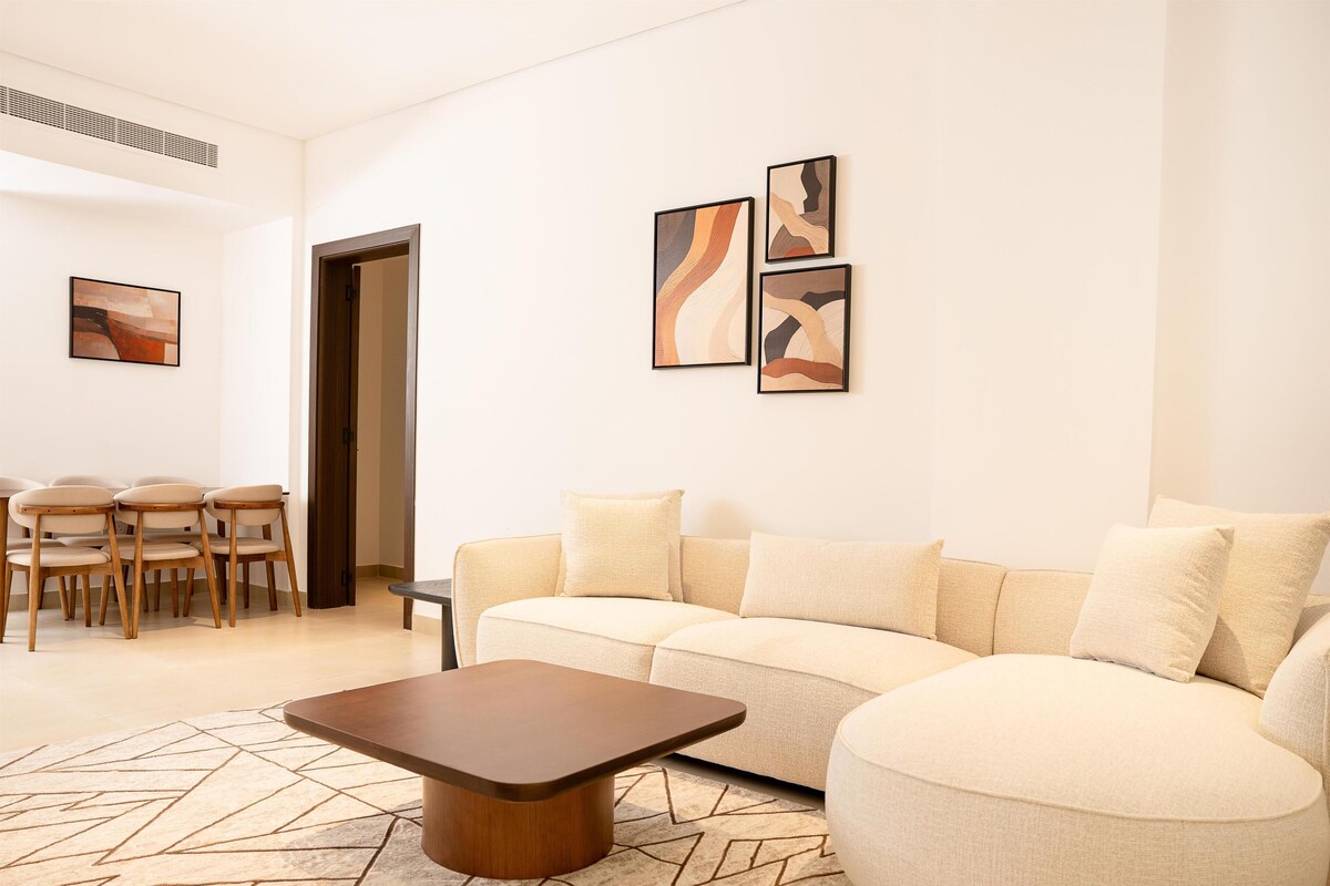 Un salon moderne avec un canapé, une table basse et des œuvres d’art accrochées au mur.