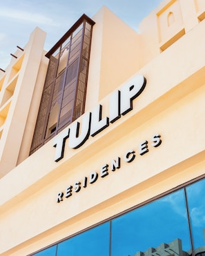 Egy épület, amelyen a „TULIP RESIDENCES” felirat található, és amely egy szállodát vagy lakókomplexumot jelöl.