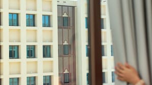 A view of a building with multiple balconies and a patterned facade through a window.